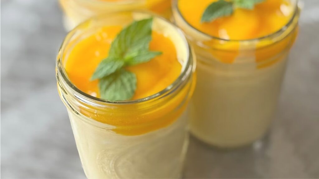 Creamy Mango Mousse served in small glass jars with bright mango topping and fresh mint leaves.