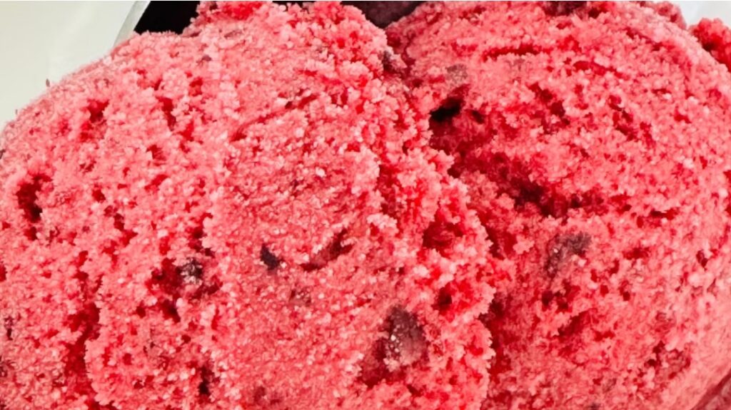 Scoops of vibrant pink forest fruit sorbet with visible pieces of mixed berries.