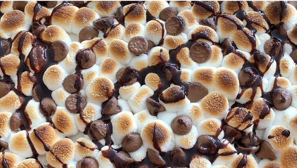 Gluten-Free Toasted Marshmallow S'more’s Pie topped with toasted mini marshmallows, milk chocolate pieces, and chocolate drizzle.