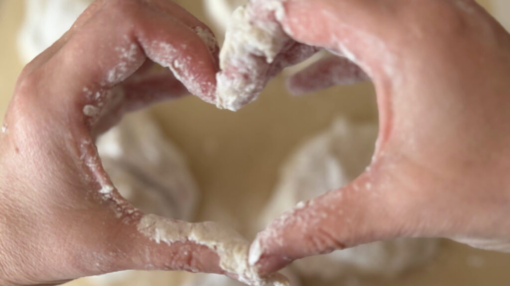 Flour-covered hands forming a heart while baking.
