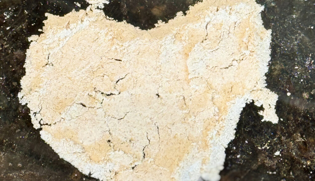 Pale flour arranged in a rustic heart shape on a dark stone countertop.