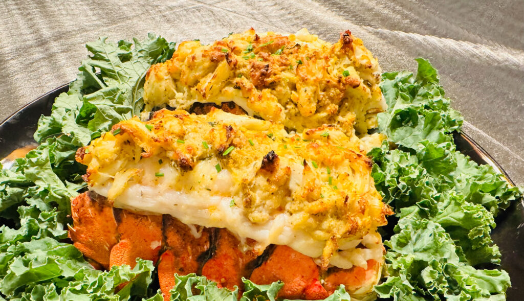 Baked stuffed lobster tails topped with golden seafood stuffing and chopped chives on a bed of fresh kale.